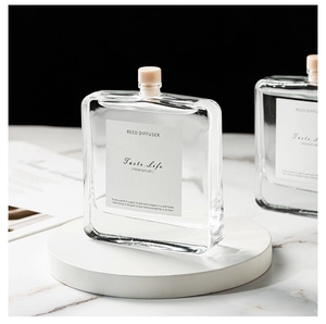 Detailed view of a square glass reed diffuser bottle with a wooden cap on marble base