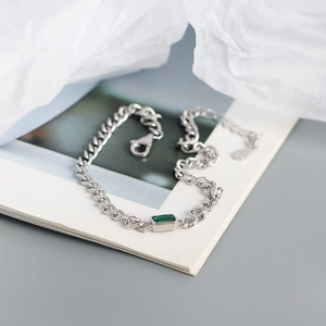Detail of S925 silver curb chain bracelet featuring a rectangular emerald green gemstone