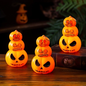 Three-tier stackable glowing pumpkin lanterns with metal handles on a rustic wooden table