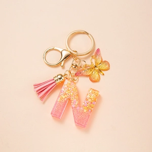 Detail of pink-yellow gradient letter N keychain with butterfly, tassel and golden clasp