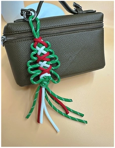 Detail of a handmade Christmas tree bag charm woven from green, red and white paracord