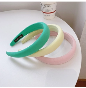 Three handmade padded sponge headbands in green, yellow, and pink colors on a white table