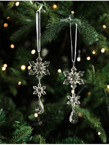 Close-up of clear acrylic snowflake ornaments hanging on a festive Christmas tree