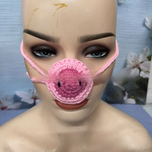 Detail shot of a hand-knitted pink pig nose warmer shown on a mannequin head