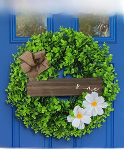 Close-up of artificial eucalyptus wreath with wooden home sweet home sign and white flowers