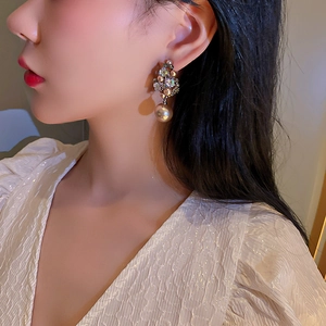Close-up of floral crystal earrings with champagne pearl drop on model's ear