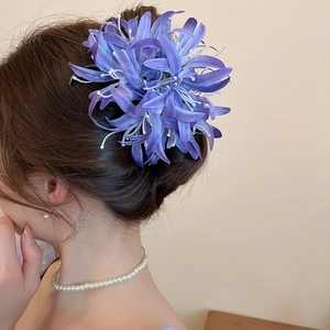 Détail d'une grande pince à cheveux en fleur de tissu violette portée sur un chignon