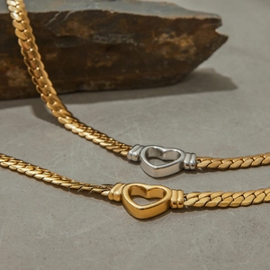 Detailed view of two gold snake bone chain necklaces featuring silver and gold heart pendants