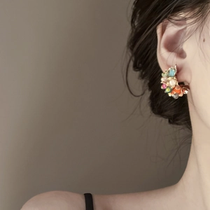 Close-up of floral tassel earrings featuring colorful crystals worn by a model