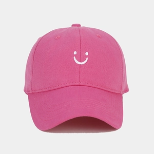 Detail of pink cotton baseball cap featuring white embroidered smiley face and vent holes