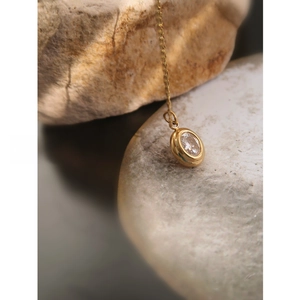 Macro view of oval cubic zirconia pendant on gold plated titanium steel chain