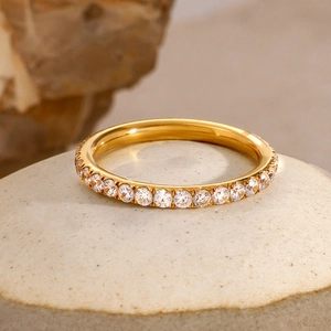 Macro shot of gold eternity ring with round cubic zirconia on a textured stone base
