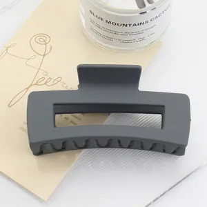 Close-up of matte dark gray rectangular hair claw clip on aesthetic floral card