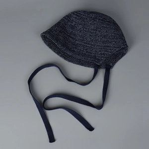 Close-up of deep blue knitted bucket hat texture and long knit straps on flat lay