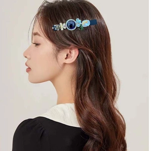 Detailed view of a sweet floral crystal hair clip worn on model's side hair