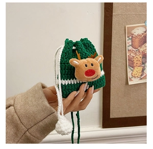 Detail of green handmade crochet reindeer pouch with drawstrings and white pom-poms