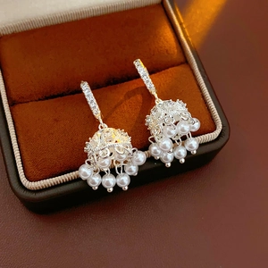 Detail of silver tassel earrings with pearls and zircon in a brown velvet jewelry box