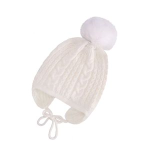 Close-up of white cable knit baby winter hat with plush faux fur pompom and earflaps