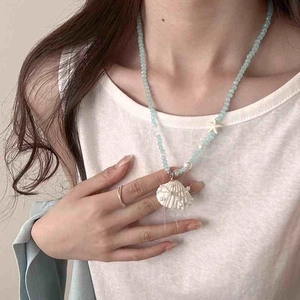 Detailed shot of starfish and shell pendant necklace with pearl fringe and blue beads