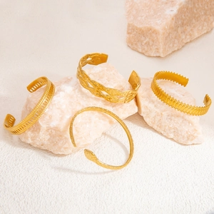 Set of four vintage 18k gold plated stainless steel open cuff bracelets on stone display