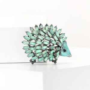 Macro shot of hedgehog brooch featuring light green rhinestones and blue enamel head