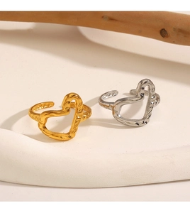 Artistic detail of gold and silver irregular heart rings on a textured pedestal