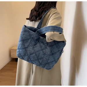 Grand sac cabas en denim matelassé bleu avec surpiqûres en losange porté par un mannequin