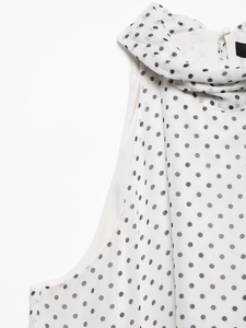 Detail of white chiffon dress with black polka dots and elegant pleated halter neckline