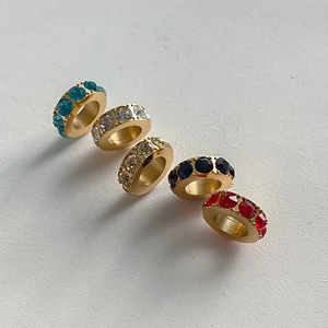 Close-up of gold-plated stainless steel spacer beads with colorful rhinestones for DIY jewelry.