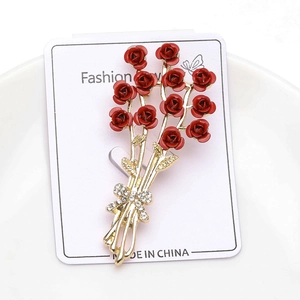 Detail of red rose brooch with golden stem, ribbon bow and crystal rhinestones