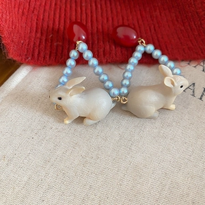 Détail de boucles d'oreilles lapin vintage avec base rouge et perles bleues