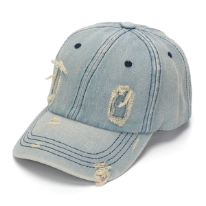Detailed side view of light blue washed denim baseball cap with distressed hole accents