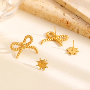 Détail de boucles d'oreilles dorées en forme de nœud et soleil sur pierre naturelle