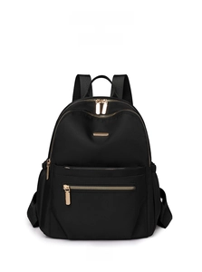 Detail of high-density black nylon backpack with gold hardware and front zipper pocket