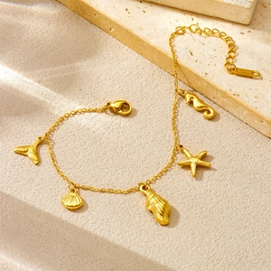 Gold stainless steel bracelet with starfish and seashell charms on textured stone