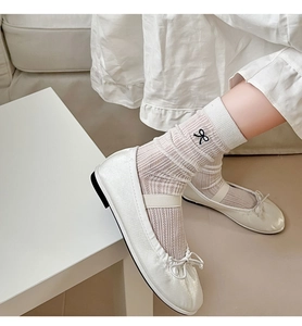 Detail showing white ribbed socks with black bows and matching ballet flats on a model