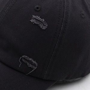 Detailed close-up of distressed ripped texture on a vintage black cotton baseball cap