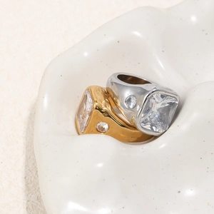 Macro shot of gold and silver chunky rings with square zircons on ceramic tray