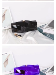 Close-up of wavy texture acrylic clutch bags in metallic black and purple finish