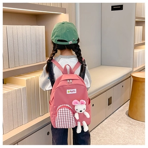 Detail of pink kids backpack with checkered pocket and cute white rabbit plush charm