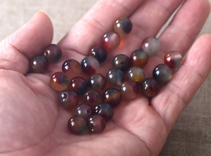 Macro view of 8mm natural mixed agate beads held in hand for jewelry DIY projects