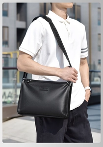 Close-up of black lychee grain leather shoulder bag with logo strap on male model