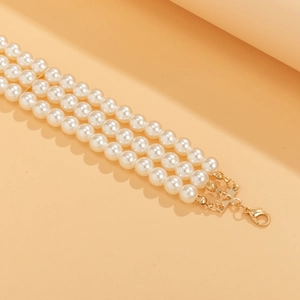 Close-up of triple-layer pearl bracelet with golden lobster clasp on warm background