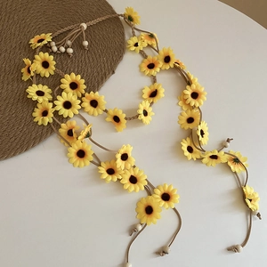 Detail eines Boho-Sonnenblumen-Haarbands mit gelben Blüten, Kordeln und Holzperlen
