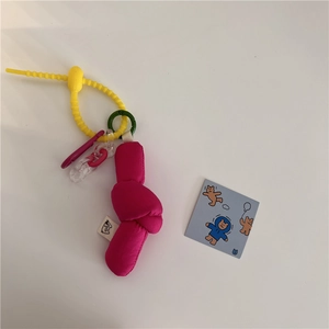 Detail of fabric knot bag charm in magenta with yellow silicone strap and cartoon card