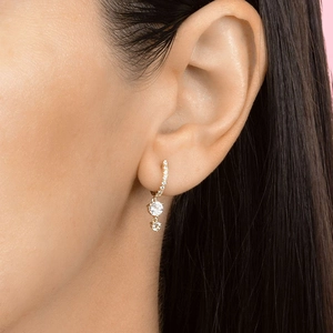 Three-stone vertical zircon drop earrings in gold finish on a model side profile