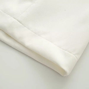 Vista macro dettagliata che mostra le cuciture precise del tessuto bianco e la trama dell'abito