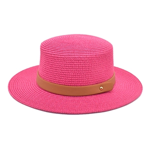 Detail view of pink straw hat with brown leather band and gold buckle on flat brim