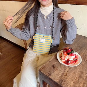Détail d'un petit sac bandoulière en peluche à rayures porté par un mannequin au café