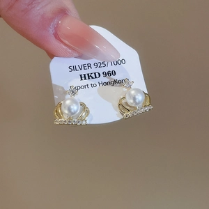 Close-up of 925 silver crown earrings with white pearl and sparkling zircon details